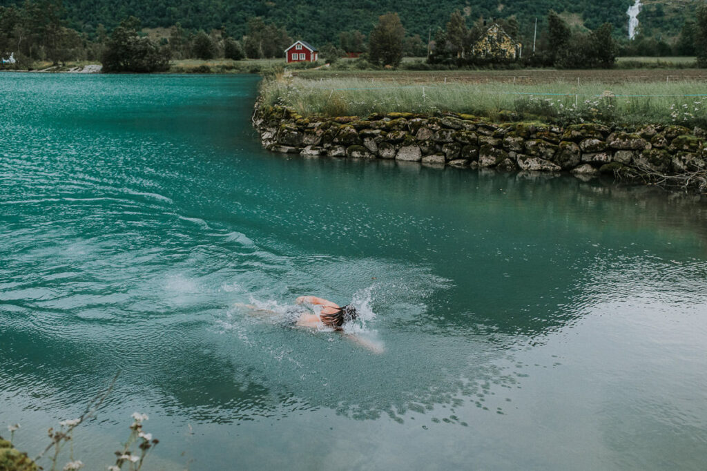 A groom swimming in a beautiful lake Oldevatnet in Western Norway at the end of their wedding day