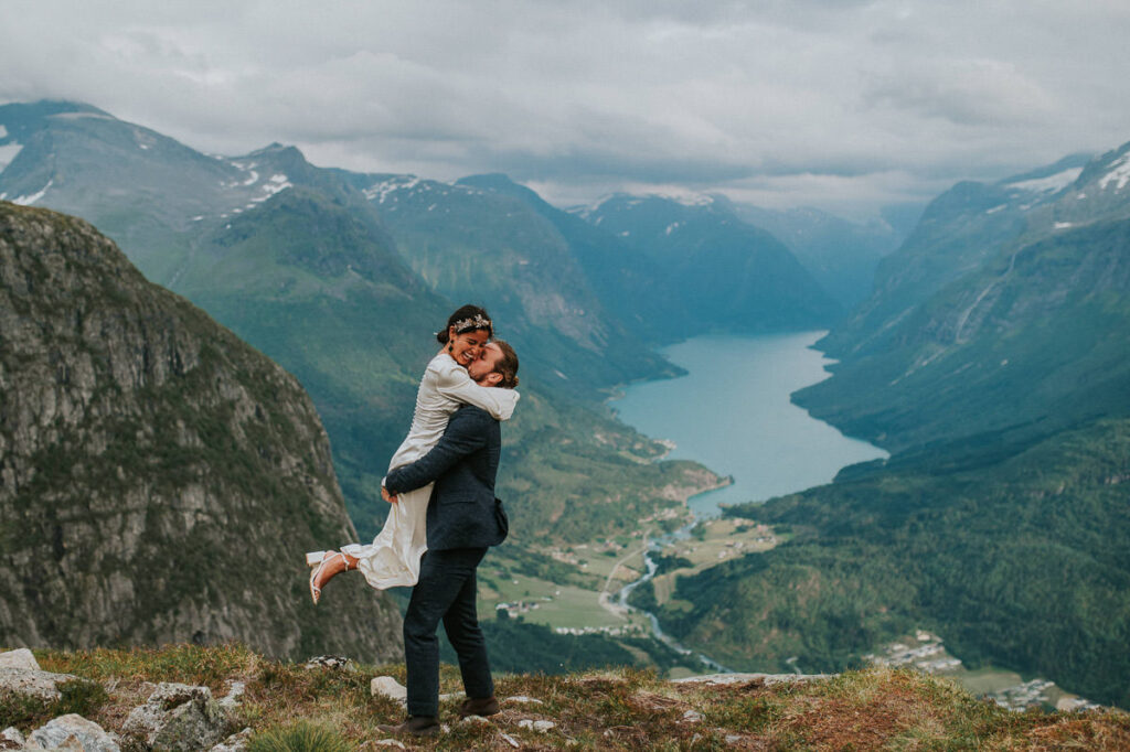 Bride and groom hugging each other in front of a gorgeous view to Lovatnet lake and fjords of Western Norway on the day of their adventure elopement in Loen