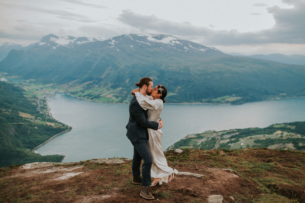 Bride and groom kissing on a mountaintop Hoven in Loen overlooking the Nordfjord on the day of their elopement