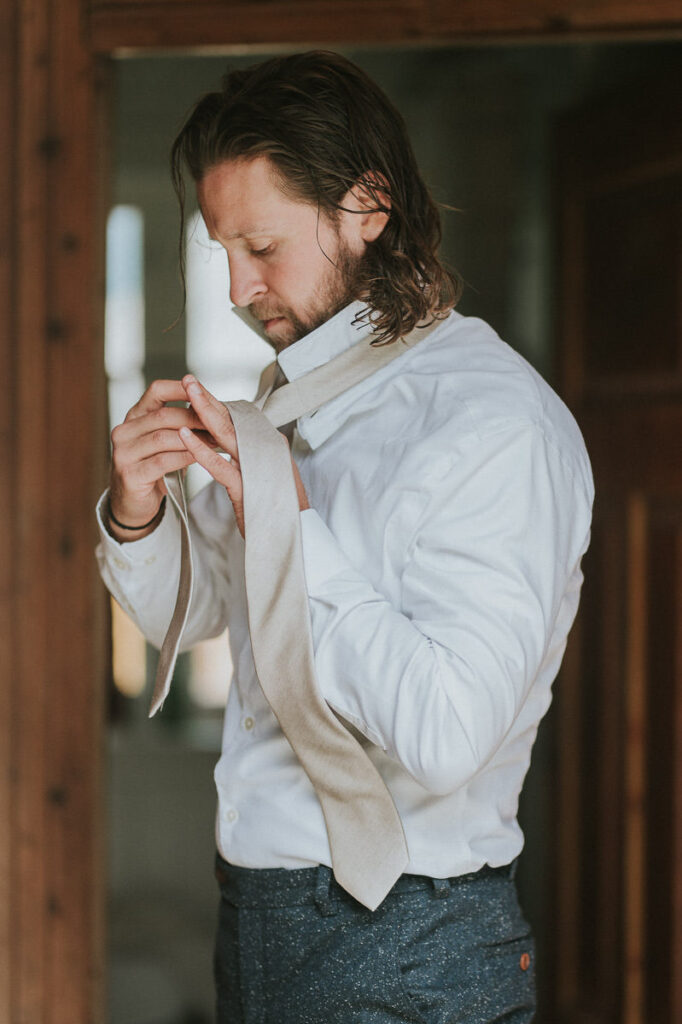 Groom getting ready for her elopement day in a cozy airbnb in Western Norway