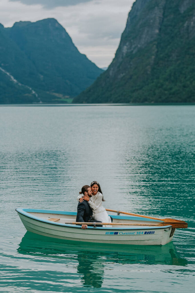 Bridal couple rowing a boat on a gorgeous blue lake Oldevatnet in Loen Stryn Western Norway on the day of their elopement