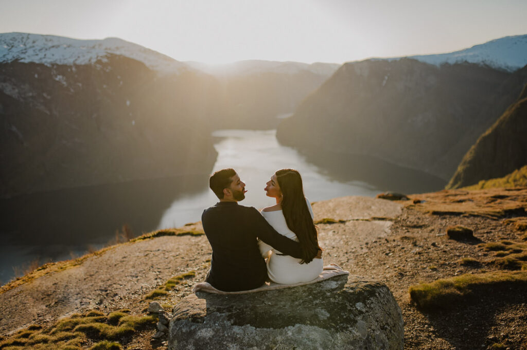 Happy couple in the mountains of Western Norway sitting on the ground and playing around