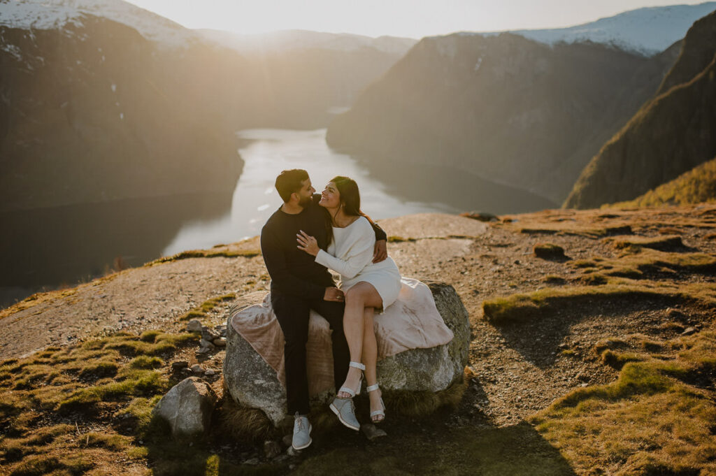 Happy couple in the mountains of Aurland Norway sitting on a mountaintop and enjoying the sunset