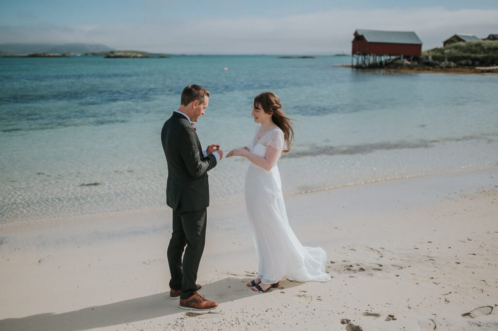 Elopement ceremony on a beautiful beach in Sommarøy island outside of Tromsø. Bride and groom exchanging their rings front of turquoise sea 