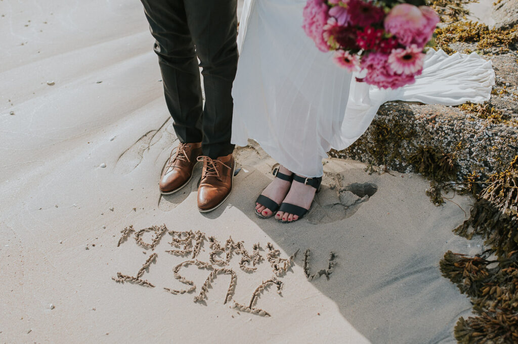 Bride and groom writing a message  Just Married in the sand on a beach 