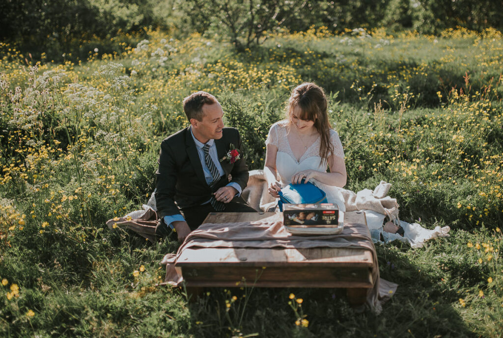 Bride and groom having a picnic in a flower field on a nice and sunny day in Sommarøy island outside of Tromsø in Norway