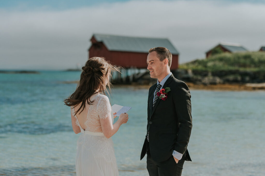 Elopement ceremony on a beautiful beach in Sommarøy island outside of Tromsø. Bride and groom reading their vows to each other in front of turquoise sea 