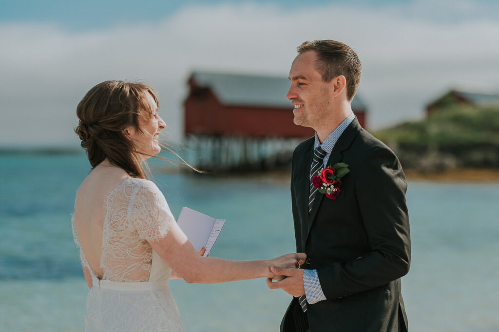 Elopement ceremony on a beautiful beach in Sommarøy island outside of Tromsø. Bride and groom reading their handwritten vows to each other in front of turquoise sea 