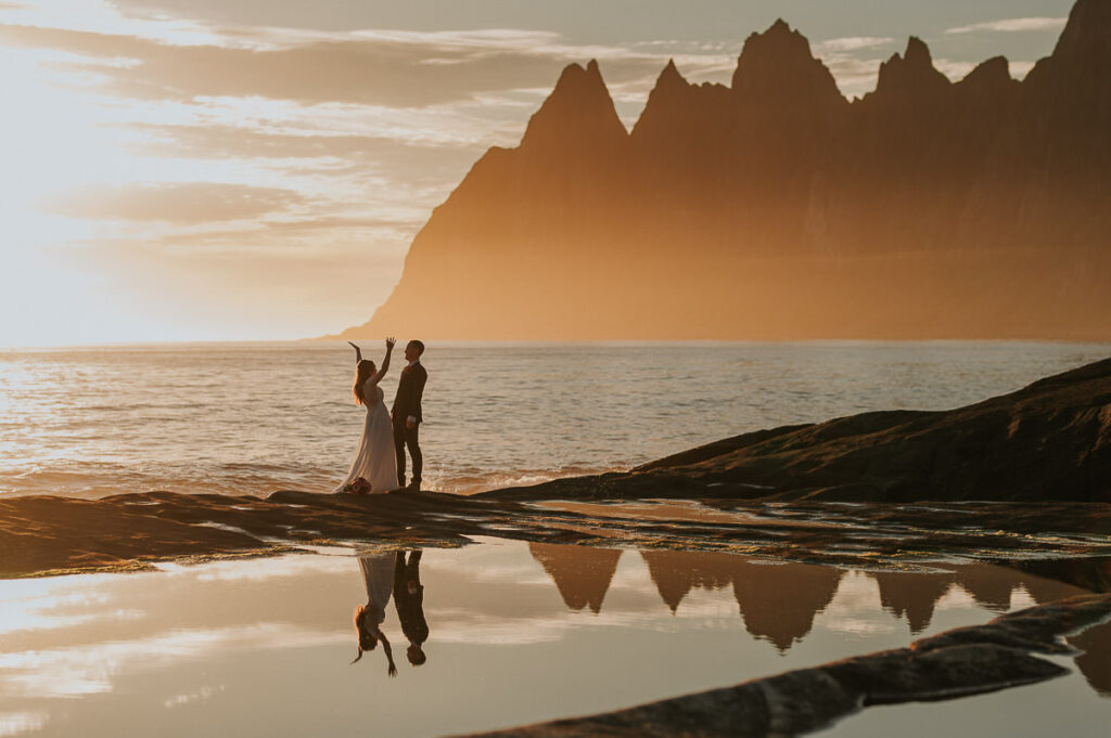 Bride and groom kissing on their elopement day in front of spectacular mountains of Senja in the gorgeous midnight sun 