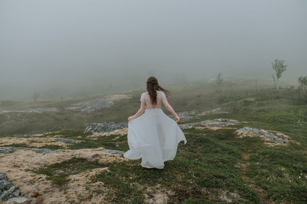 Bride dancing in front of a beautiful foggy landscap in Northern Norway