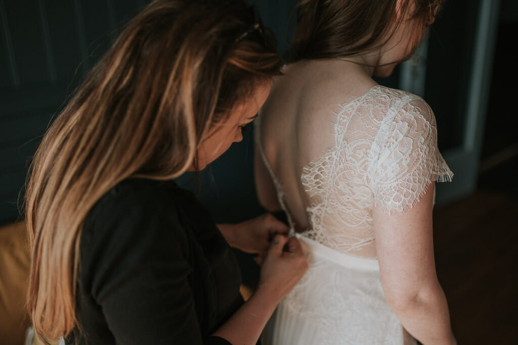 Bride is getting her lace wedding gown on before their ceremony