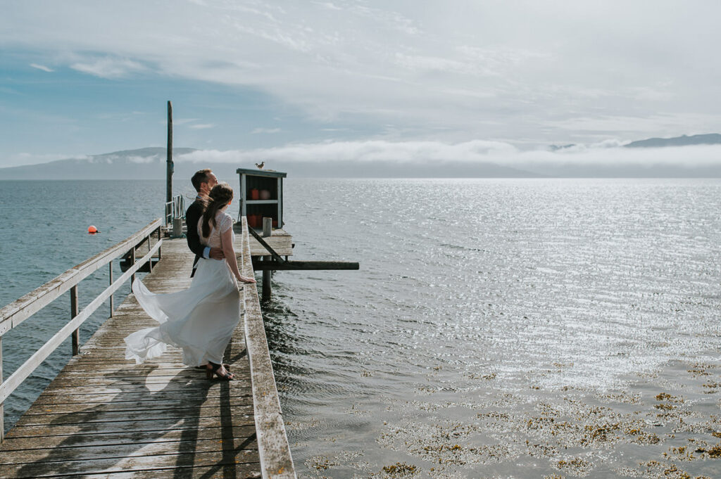 Bride and groom standing on an old wooden pier in Tromsø 