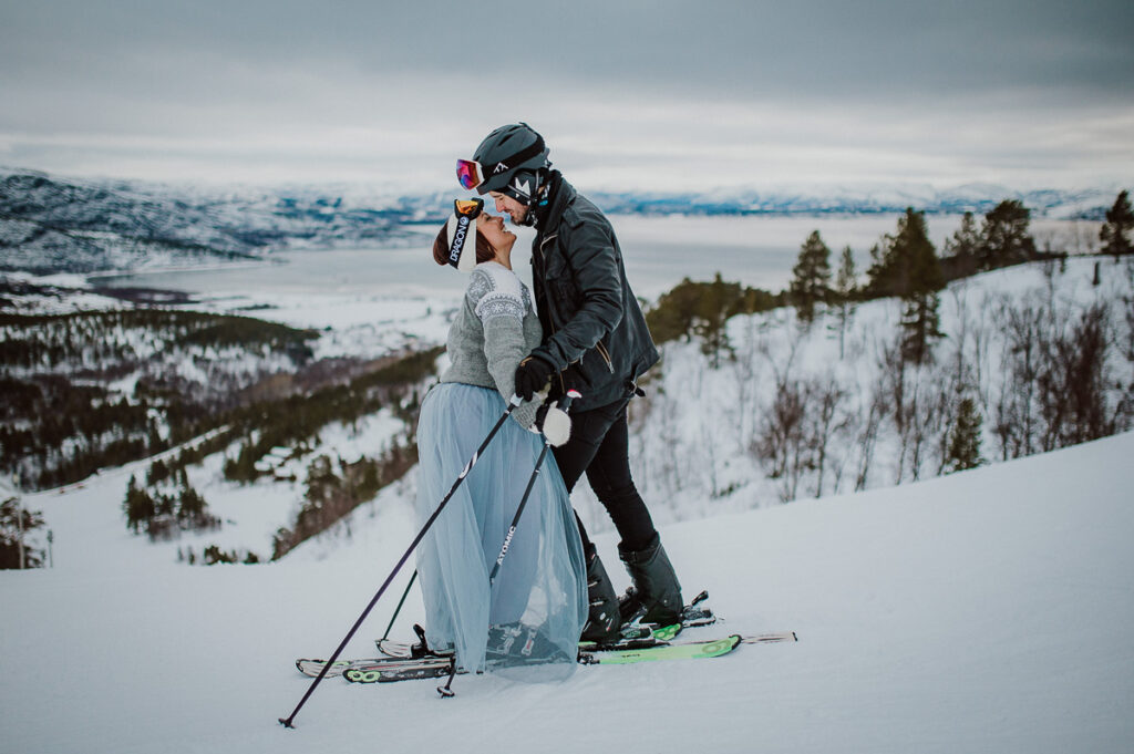Cute couple in wedding attire slalom skiing down the hills on the day of their winter elopement in Alta Norway