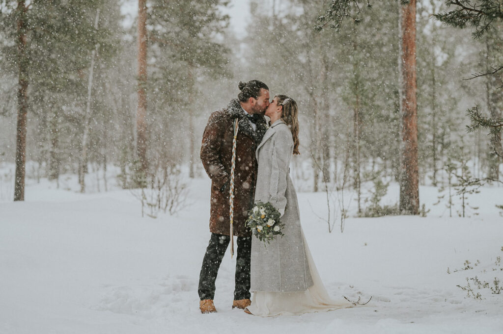 Gorgeous bride and groom kissing under a snowfall and blizzard in Alta Norway on the day of their winter elopement