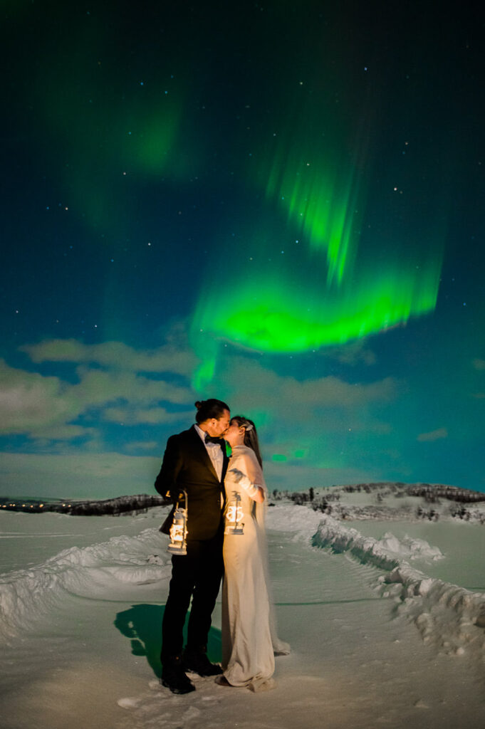 Beautiful bride and groom kissing under the northern lights on the day of their elopement in Alta Norway