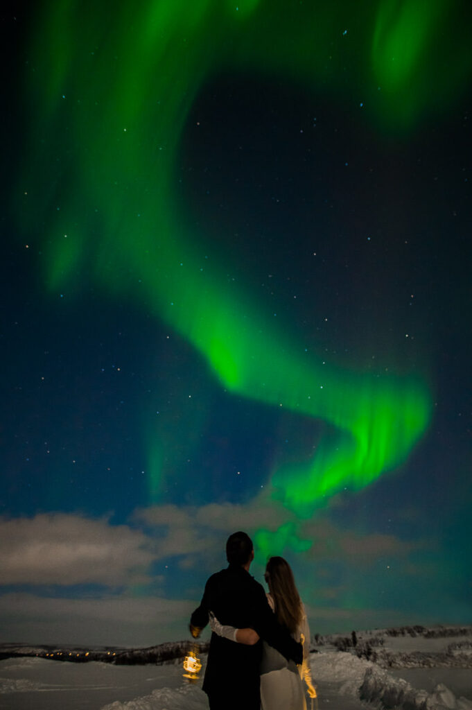 Beautiful bride and groom watching a great show of northern lights on the day of their elopement in Alta Norway