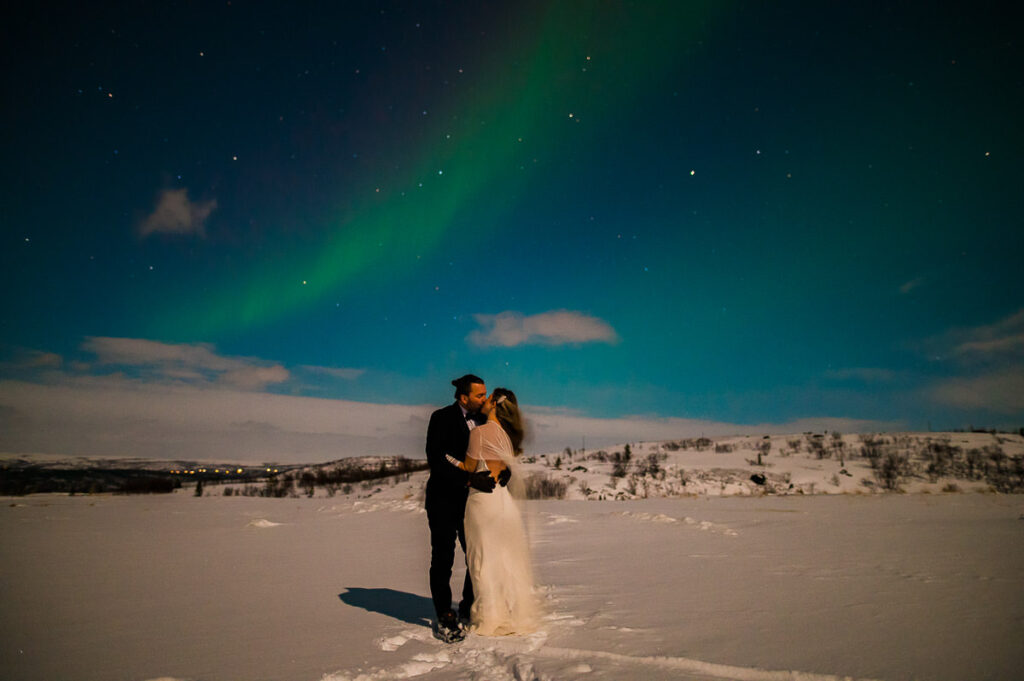 Beautiful bride and groom kissing under the northern lights on the day of their elopement in Alta Norway