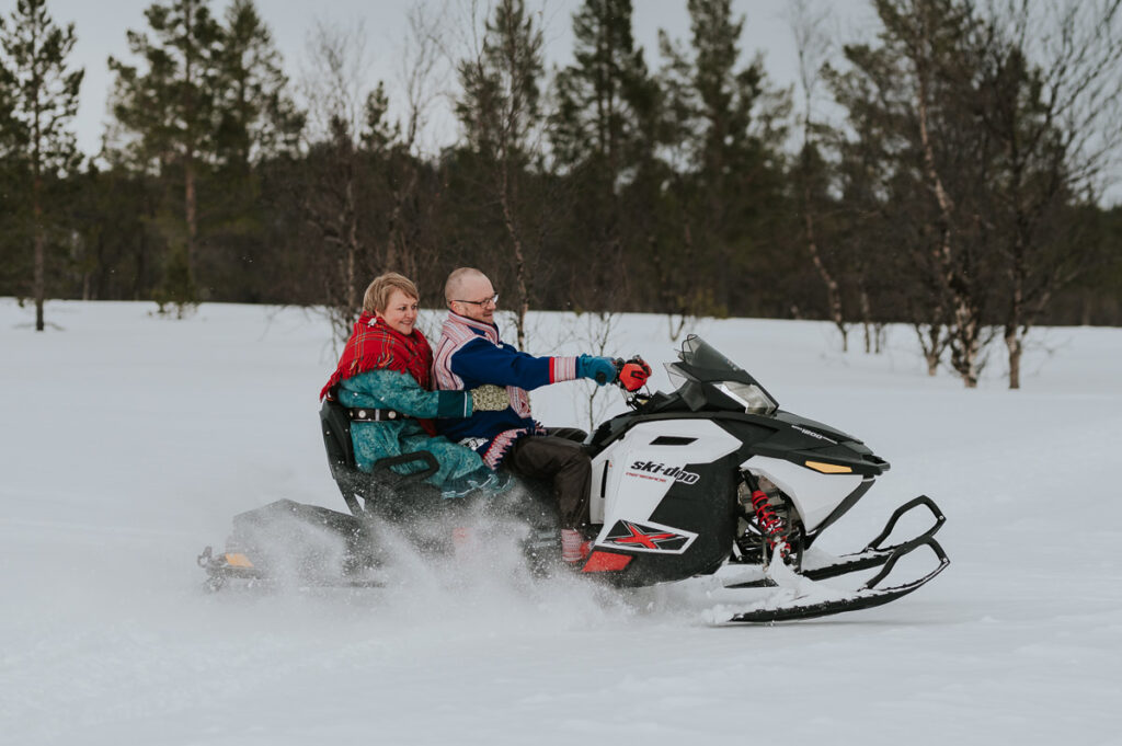 Sami couple in traditional costumes sami kofta driving snowmobile in Alta Norway