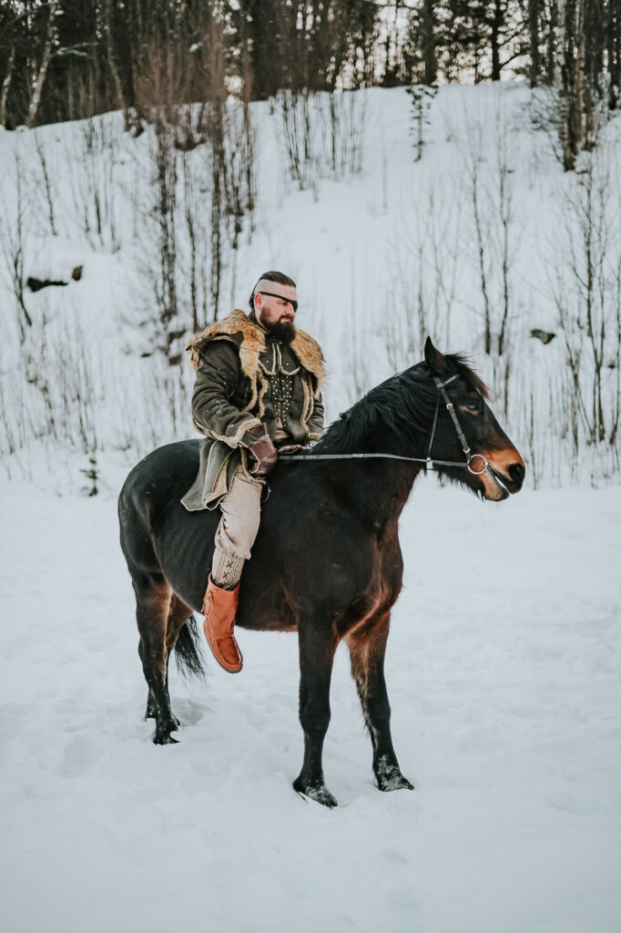 Male viking riding a horse among winter landscapes of Northern Norway