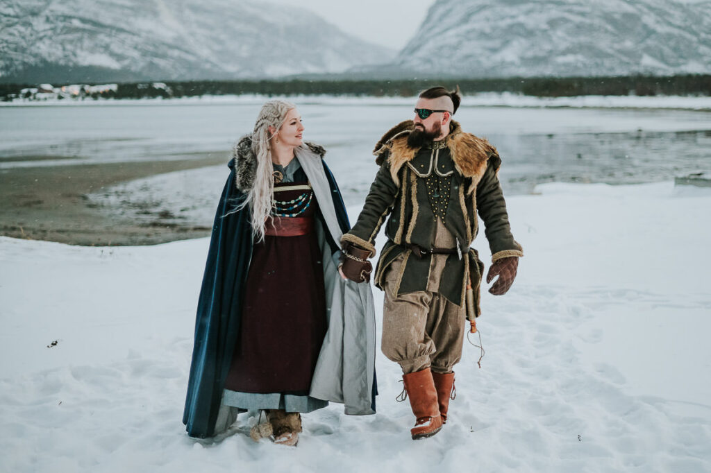 Viking couple walking among beautiful winter landscape with mountains and fjords in Alta Norway