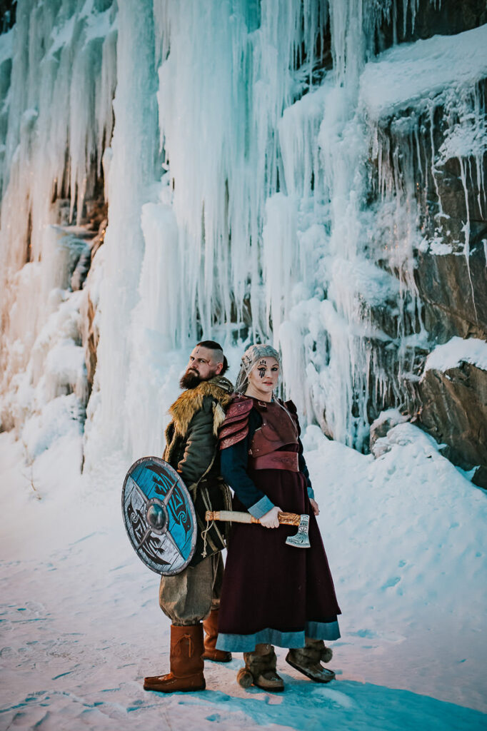 Viking style wedding portraits where the couple is posing in front of gorgeous frozen waterfalls in Northern Norway
