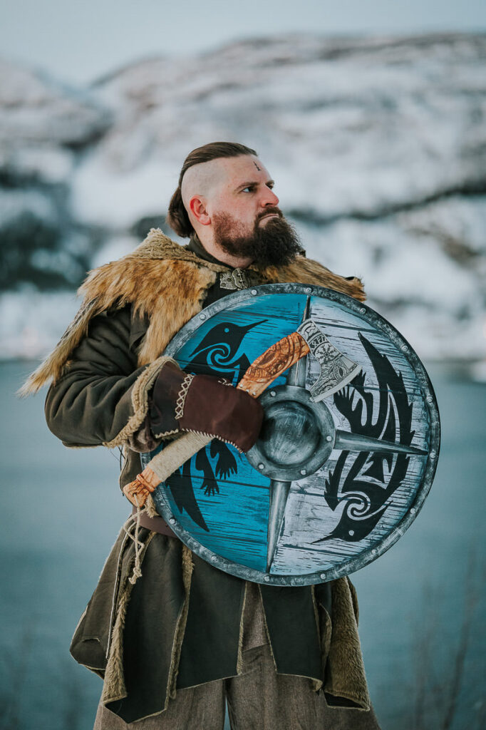 Viking man with a shield and axe in front of a snowy landscape in Alta Norway