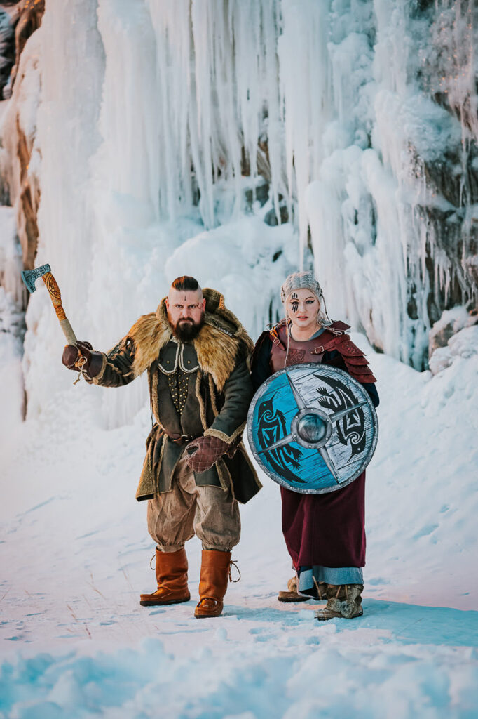 Viking couple portrait session in front of frozen waterfalls in Norway