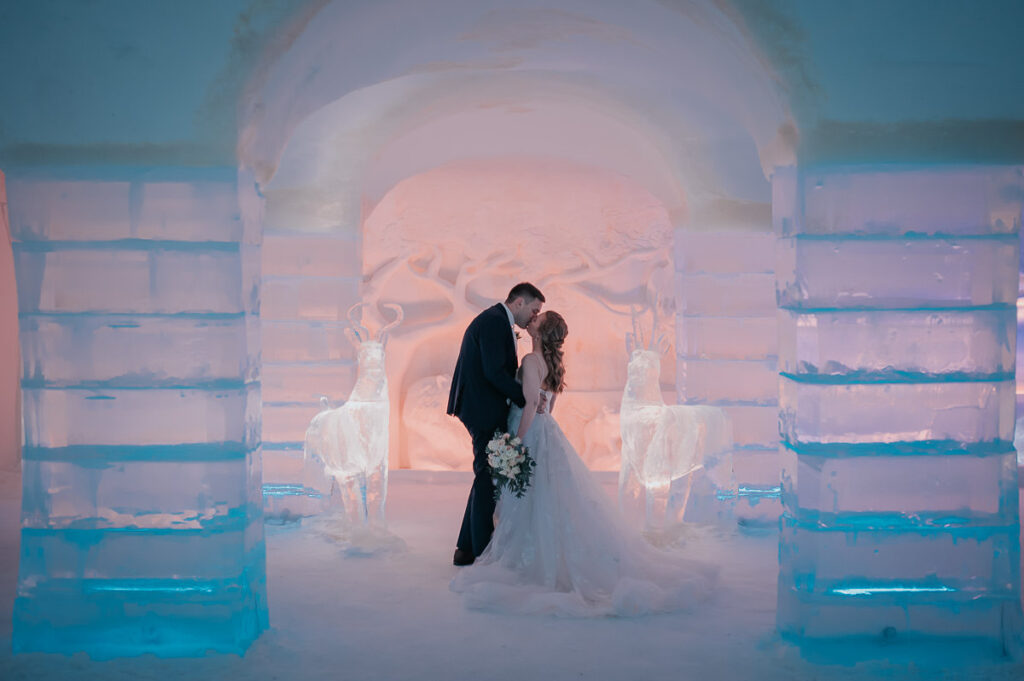 Bride and groom kissing among ice sculptures in igloo hotel Sorrisniva in Alta Norway 