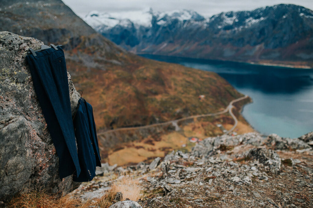 Navy blue wedding suit hanging on a rock above a beautiful fjord and mountain view in Tromsø