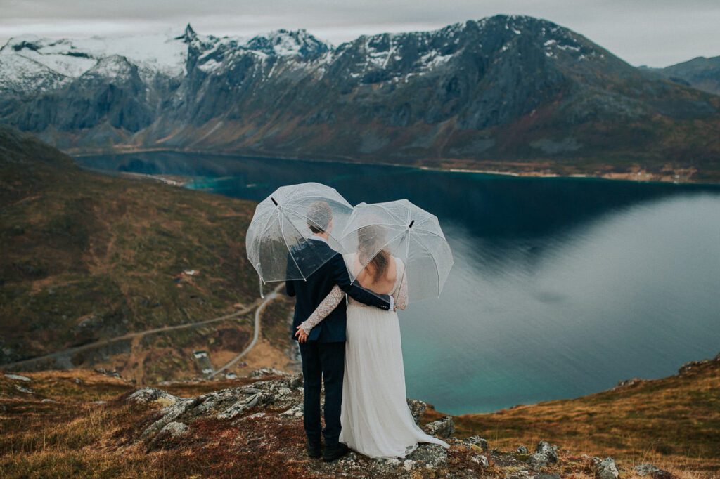 Hiking elopement in Tromsø on a rainy autumn day. Bride and groom admiring a great mountain and fjord view