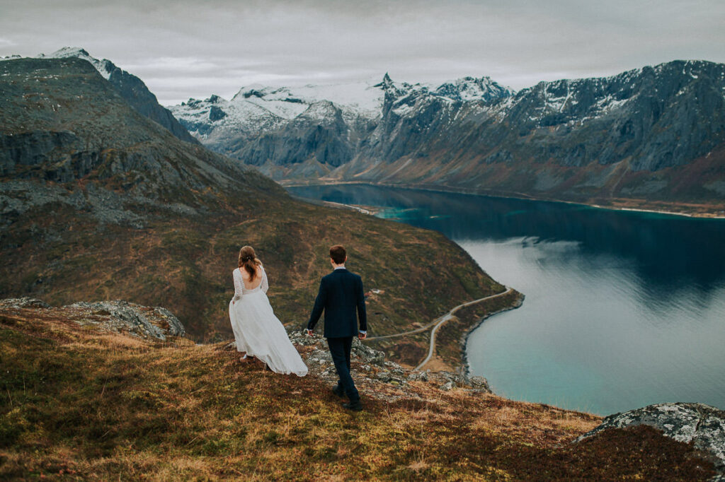 Hiking elopement in Tromsø on a rainy autumn day. Bride and groom admiring a great mountain and fjord view