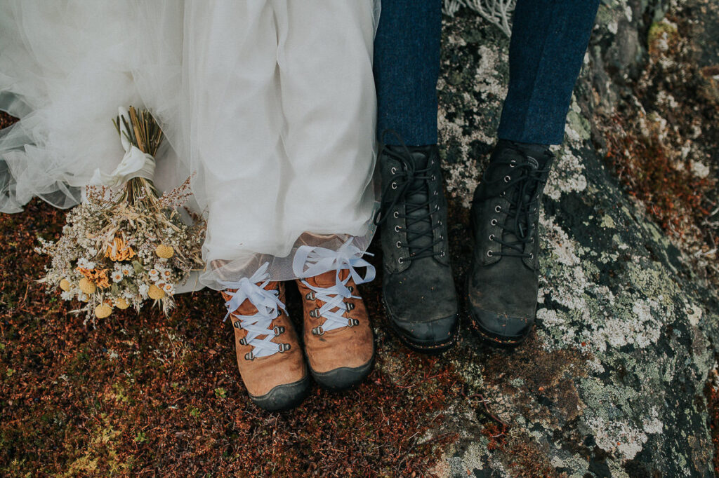 Bride and groom showing off their hiking boots on the day of their elopement in Tromsø. Bride's hiking shoes are decorated with white shoelaces