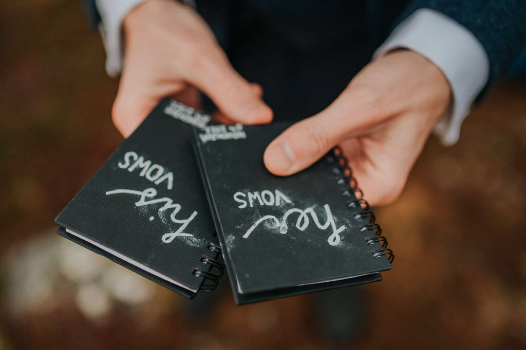 Groom holding vow books in his hands. Some rain drops eraised the hand written words on the vow books