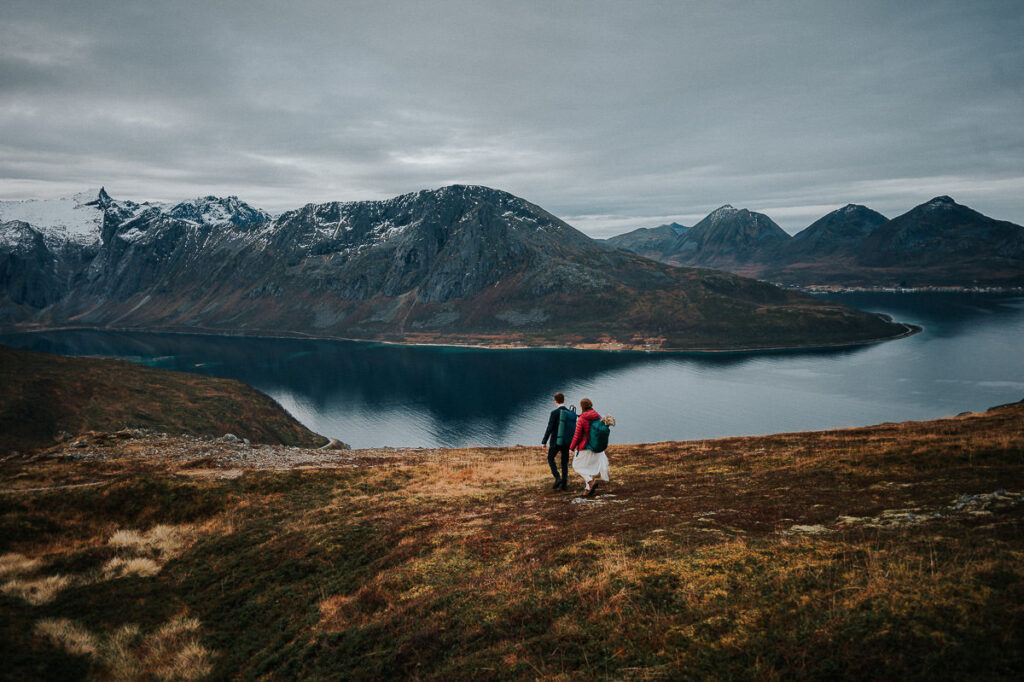 Hiking elopement in the mountains of Tromsø in Northern Norway. Bride and groom hiking among beautiful autumn colored landscapes
