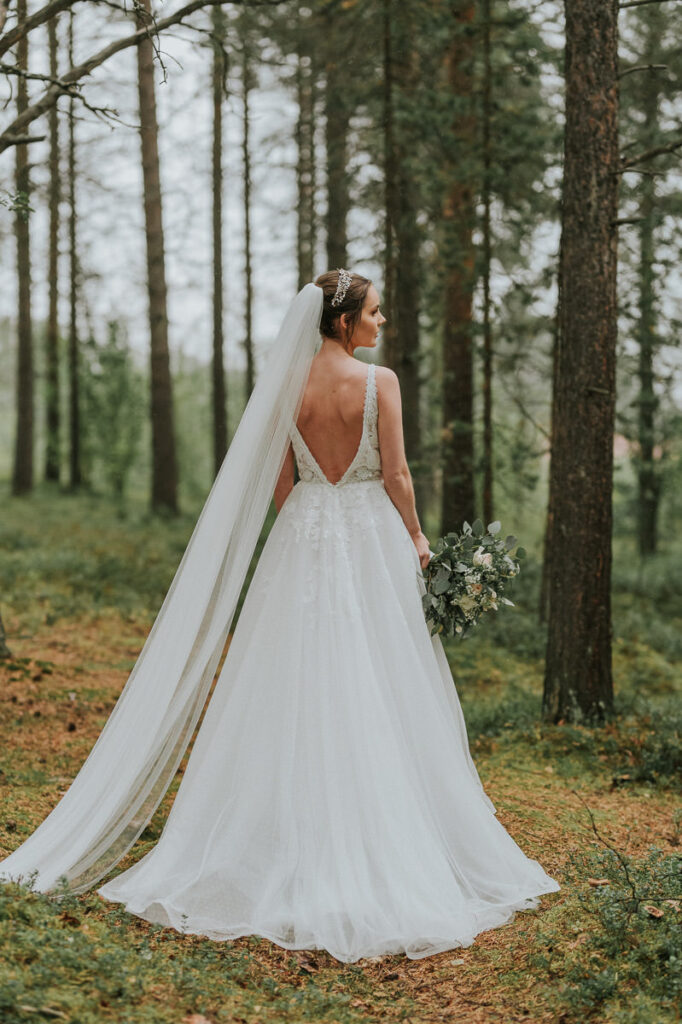 Nydelig brud i en furu skog viser frem sin vakre brudekjole