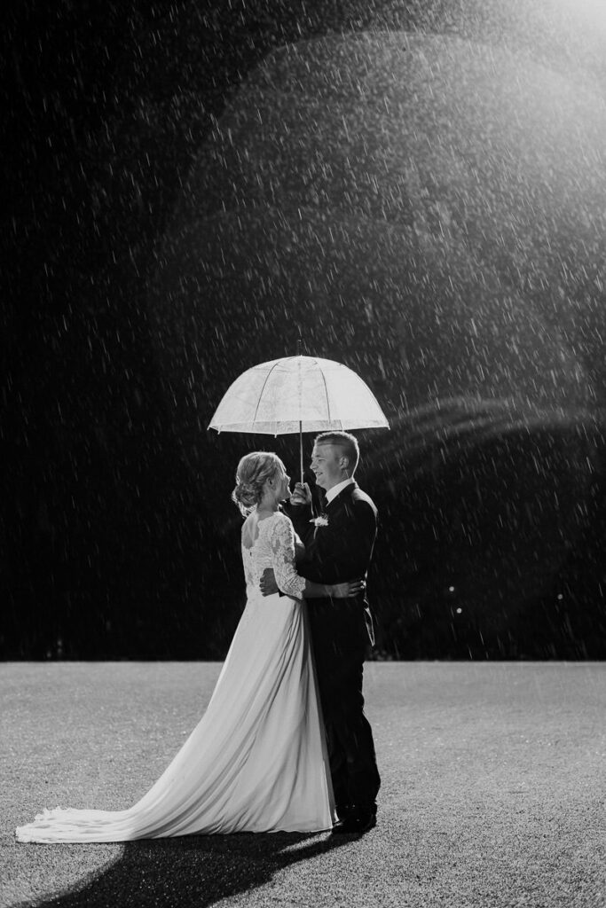 Svart hvit portrett bilde av et brudepar som kysser under paraply på en regnværsdag i Alta