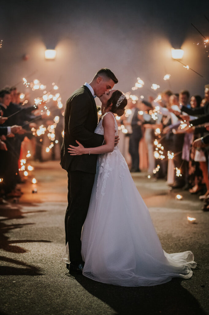 Brudepar kysser under stjerneskudd fra gjestene på slutten av bryllupsdagen sin