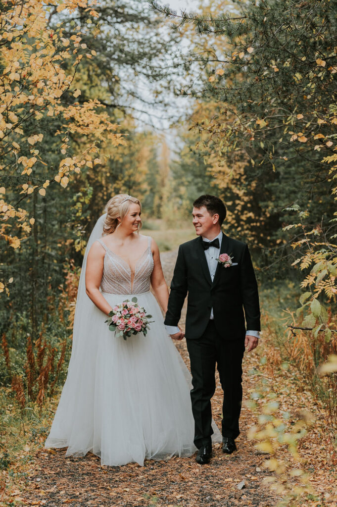 Nydelig brudepar kysser i en høstkledd skog mens fargerike bladene faller på dem - beste foto locations for bryllup i Alta