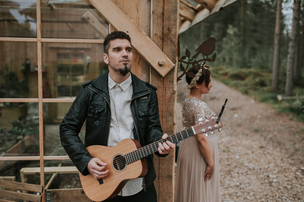 Brudgommen i en skinnjakke spiller gitar og synger til sin brud