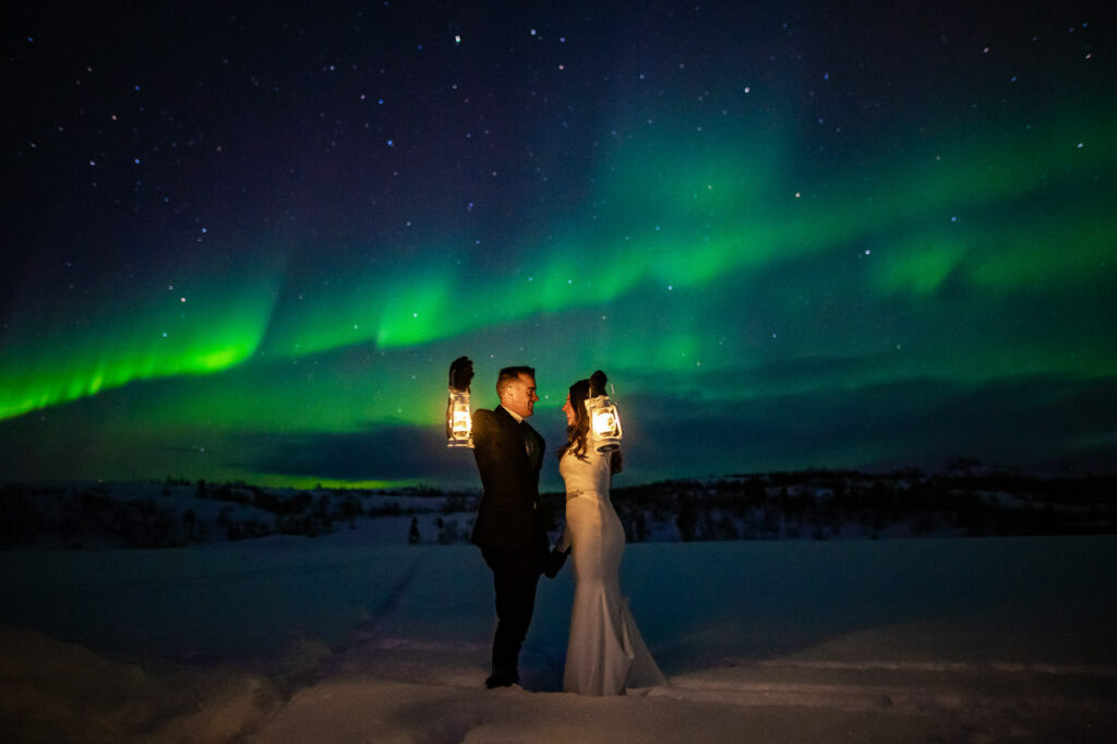 Vakkert brudepar ser på Aurora borealis show på himmelen i Alta - vinter bryllup - beste foto locations for et bryllup i Alta