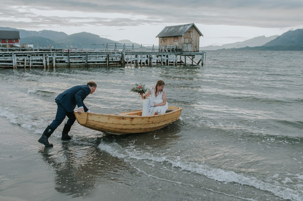 Brudgommen skyver en robåt på havet mens bruden sitter i båten