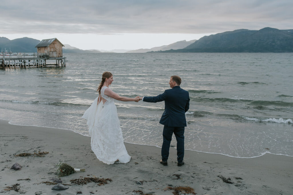 Brudepar danser på stranda med sjø og fjell utsikt utenfor Alta