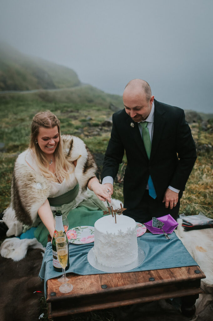 Bride and groom eating their wedding cake outdoors after their elopement wedding ceremony on Sørøya