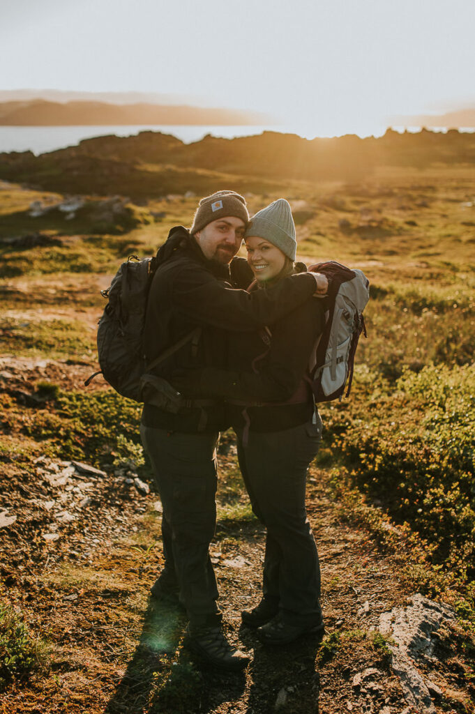 A couple with backpacks walking towards midnignt sun on Sørøya in Norway