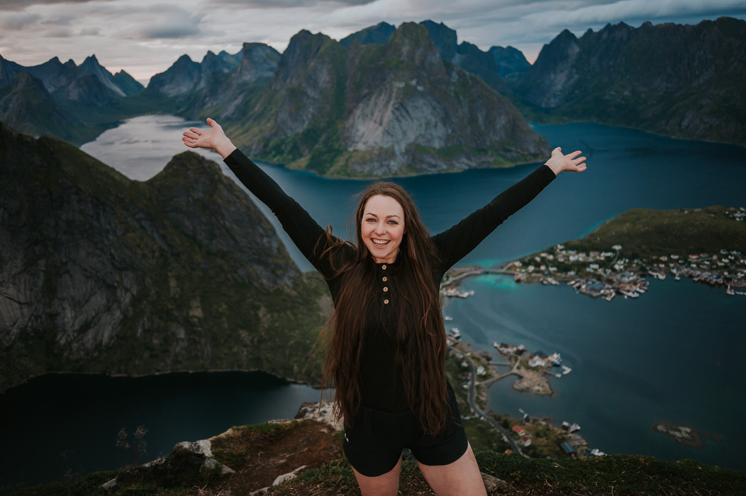 Portrait of a woman on a mountaintop vith a spectacular view over mountains and fjords in Lofoten Norway