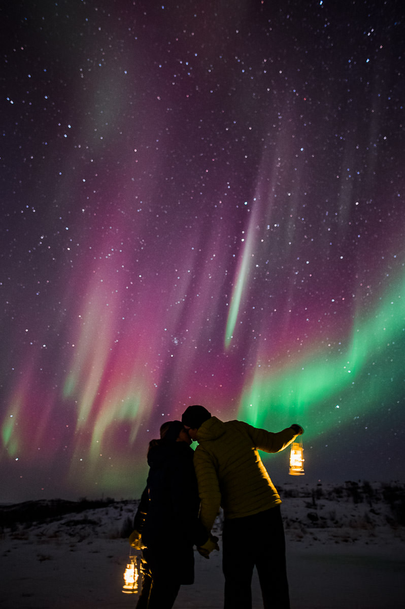 A couple kissing under the northern lights on their engagement photo session in Alta Norway