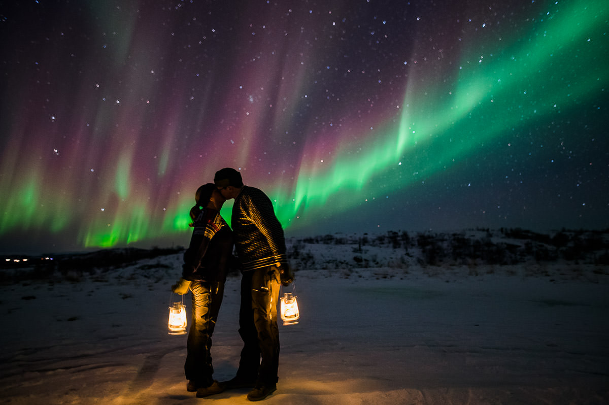 A couple kissing under the northern lights on their engagement photo session in Alta Norway