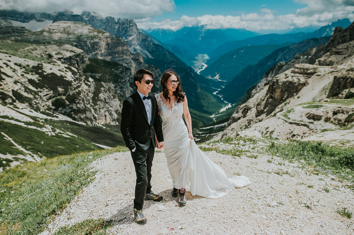 Bride and groom in sunglasses posing in the mountains Tre Cime di Lavaredo in Italian Dolomites