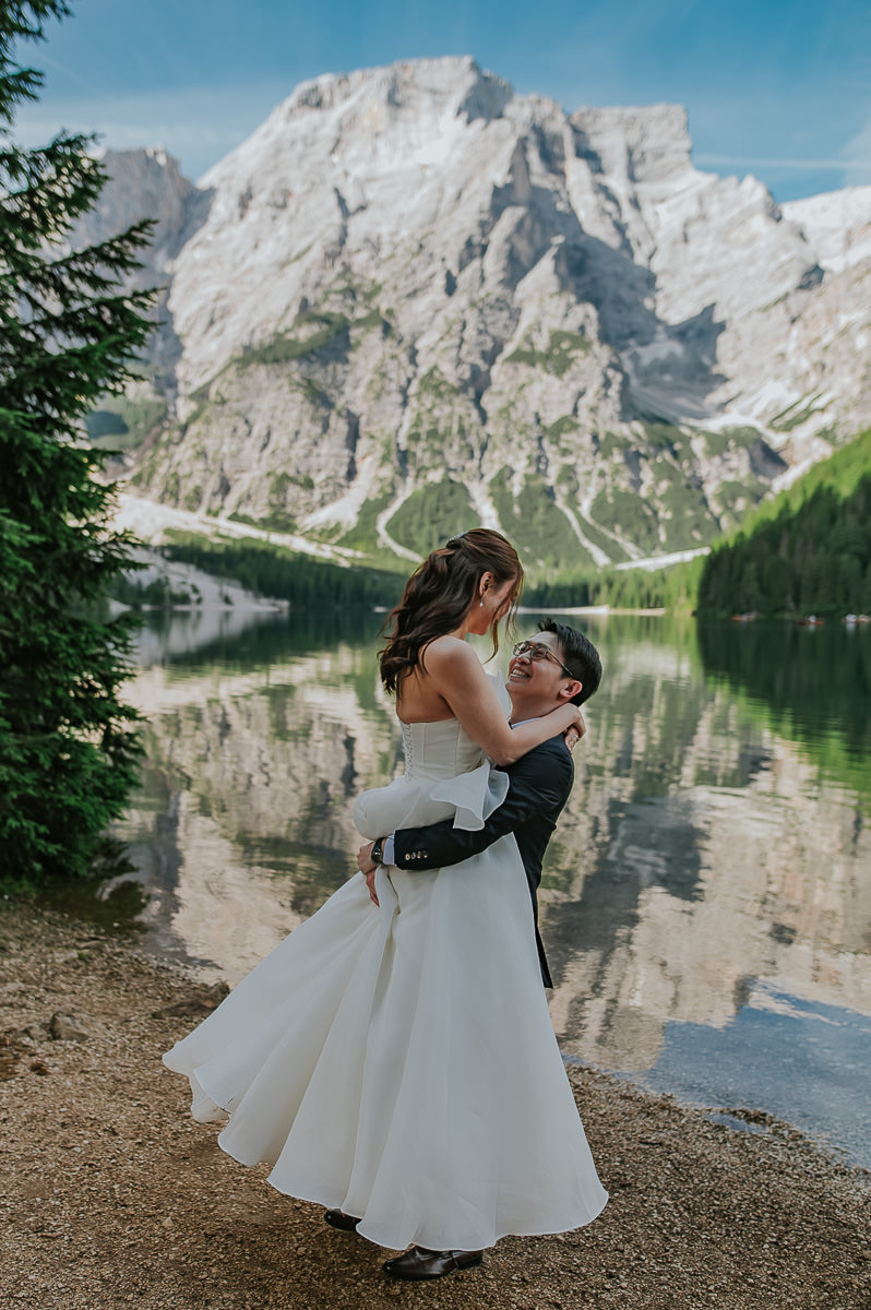 Bride and groom dancing by the lake Lago di Braies in Italian Dolomites