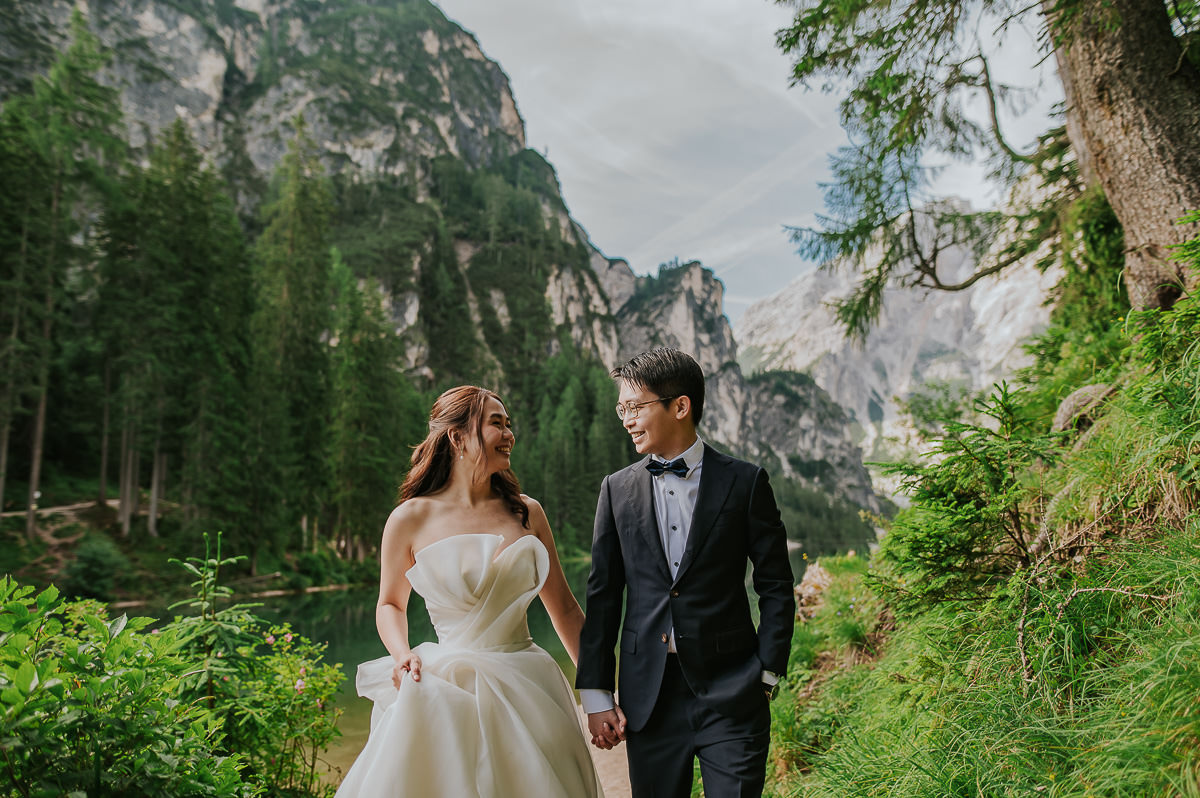 Bride and groom walking by the lake di Braies in Italian Dolomites
